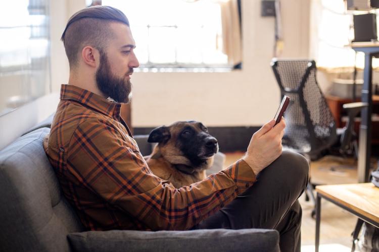 Mann mit einem SquareTrade-Ger&auml;t und einem Hund